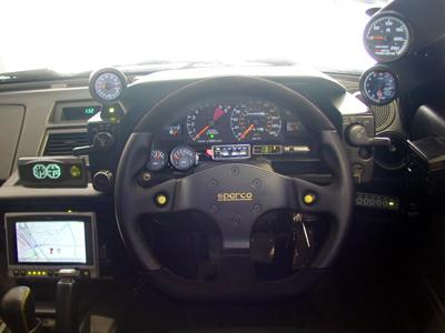 car interior with a black steering wheel and a dashboard featuring various gauges and a GPS screen