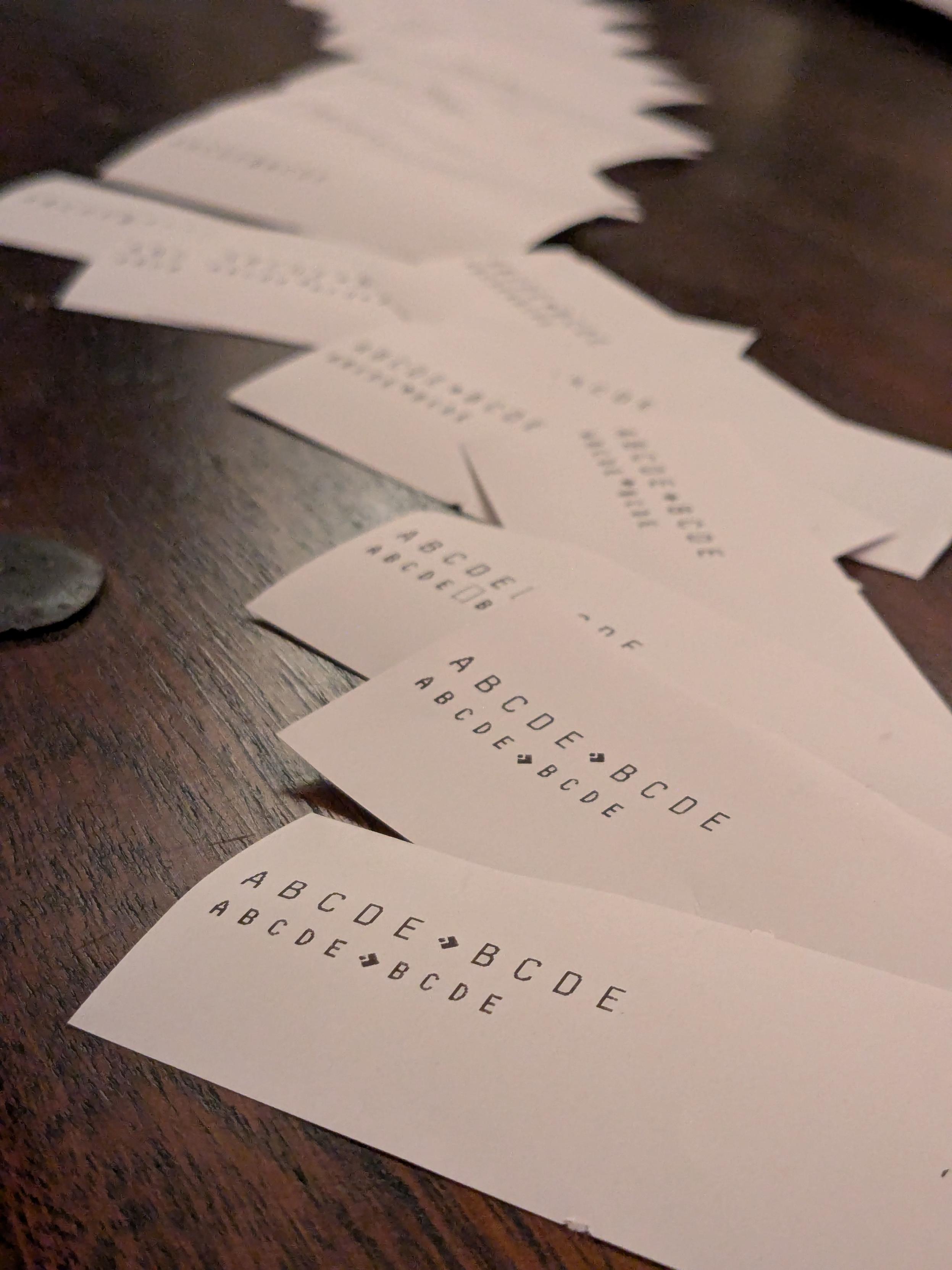 a long river of little bits of recept printer paper with "A B C D E ♦️ B C ...' etc with varying levels of success